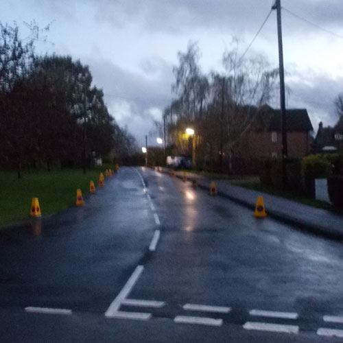 wet road with yellow police on waiting cones