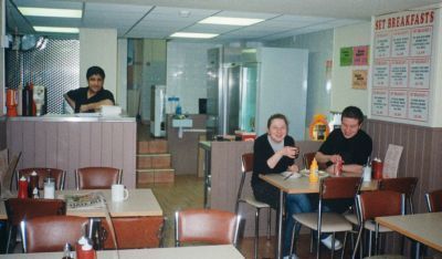 Inside of cafe with counter  and worker and people drinking tea