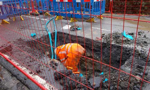 Man fixing pipe in hole