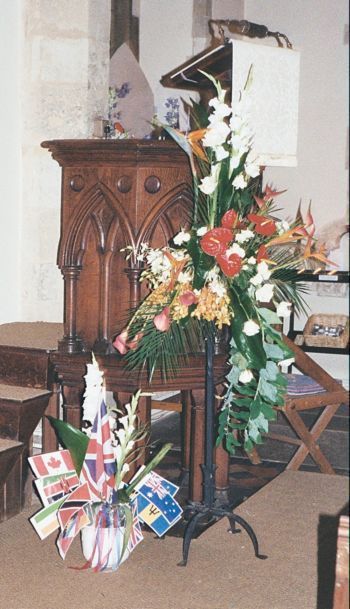 Flowers in church - by pulpit bottom of pulpit lots of flags